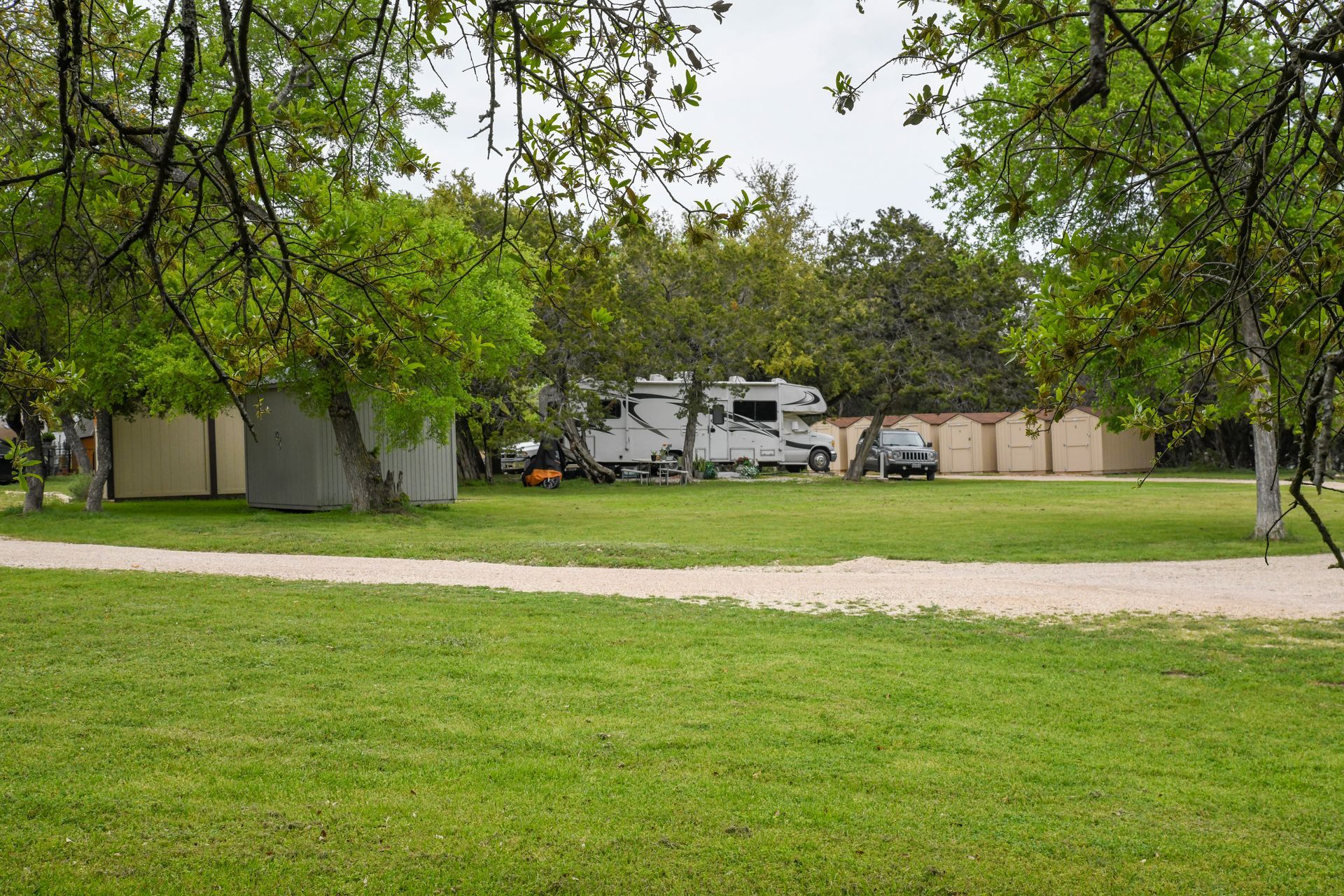 A rv is parked in a grassy field surrounded by trees.