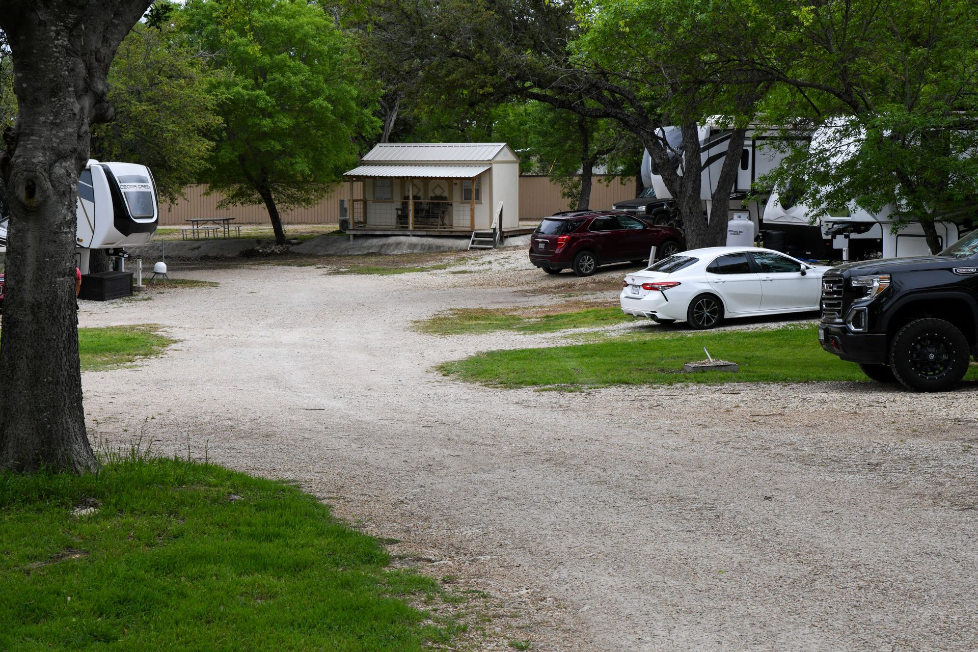 A lot of cars are parked in a gravel lot.