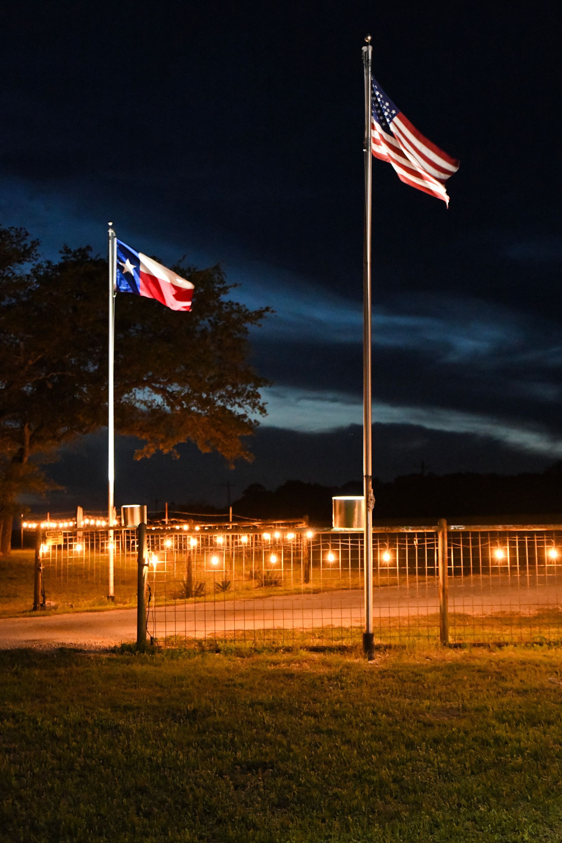 Two flags are flying in a field at night