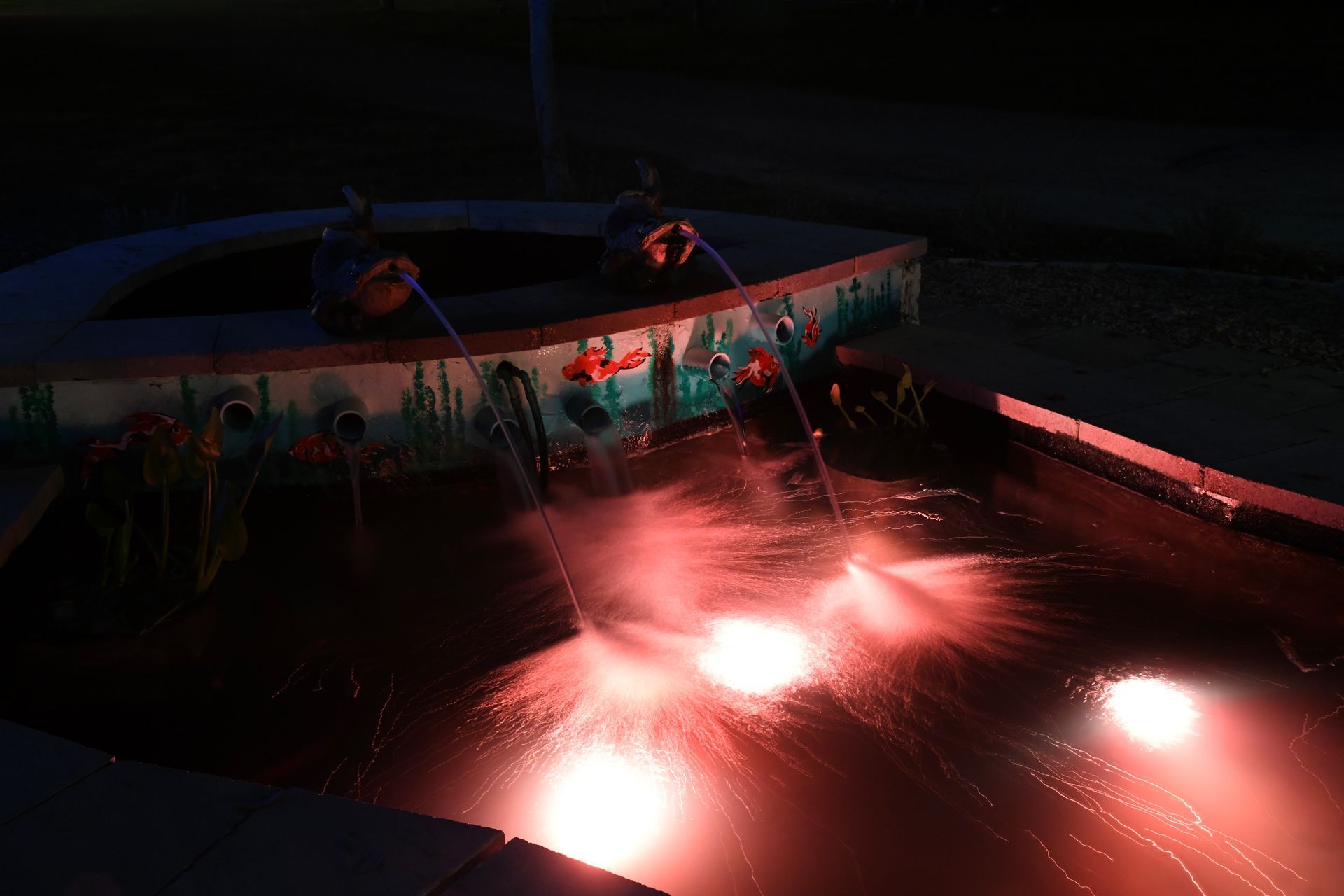 A pool with red lights on it at night.