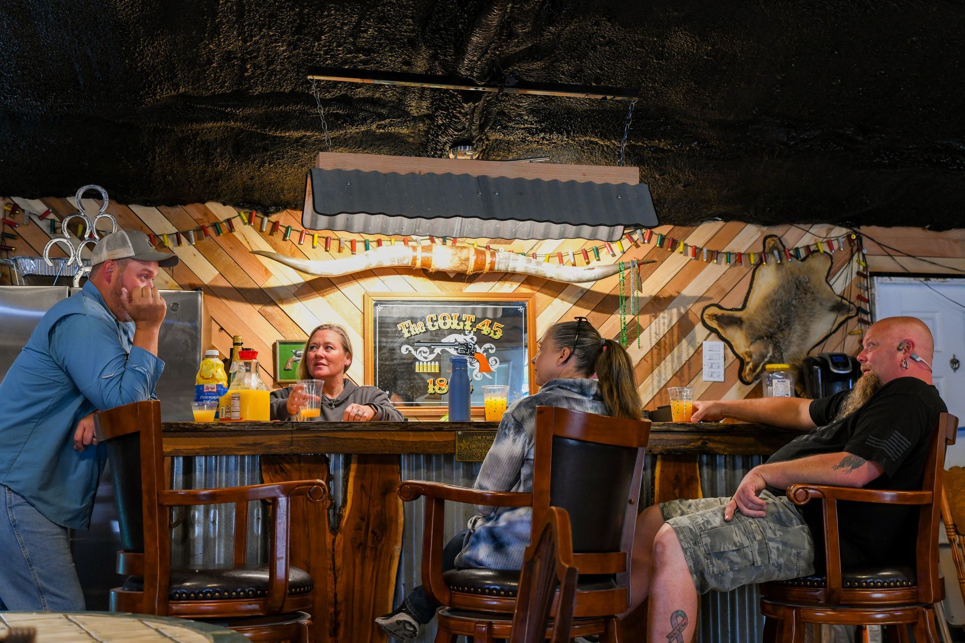 A group of people are sitting at a bar talking to each other.