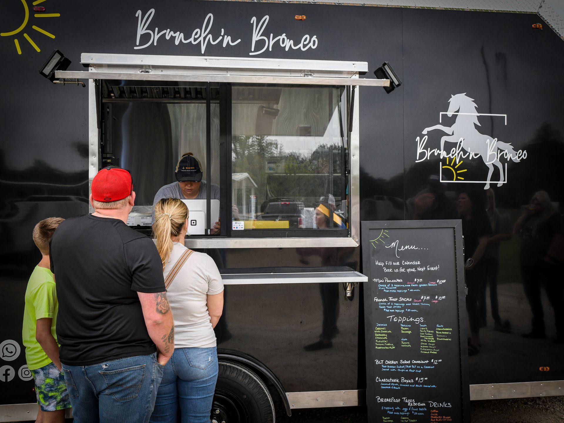 A group of people are standing in front of a food truck.
