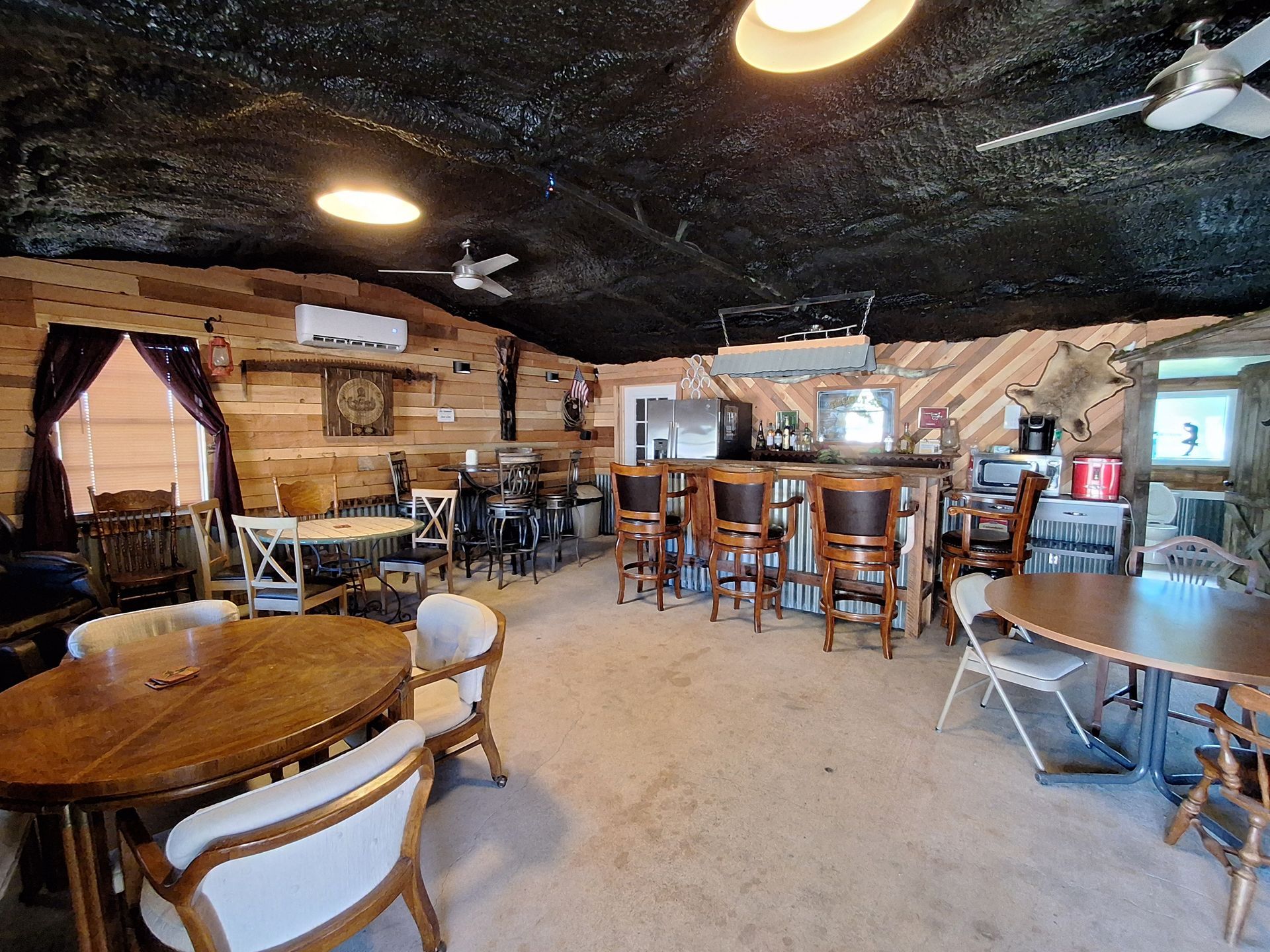 A large room with tables and chairs and a bar.