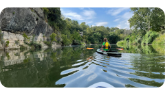 A person is riding a kayak down a river.