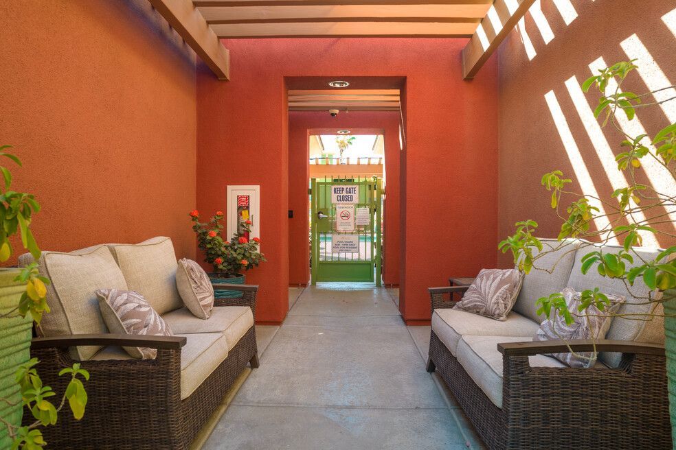 A patio with two couches and a red wall