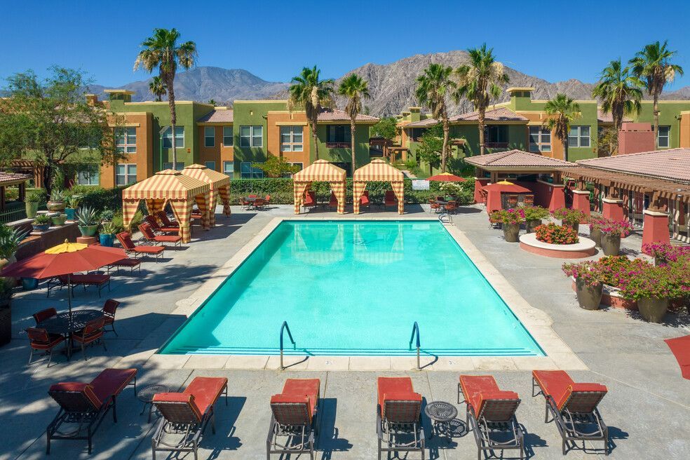 A large swimming pool surrounded by chairs and umbrellas