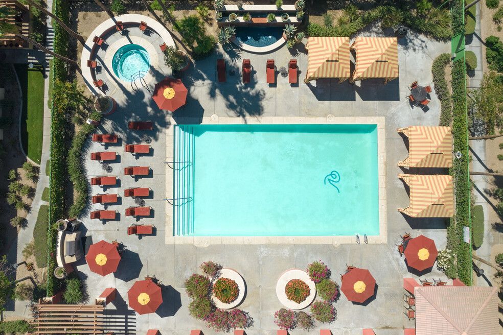 An aerial view of a large swimming pool surrounded by chairs and umbrellas