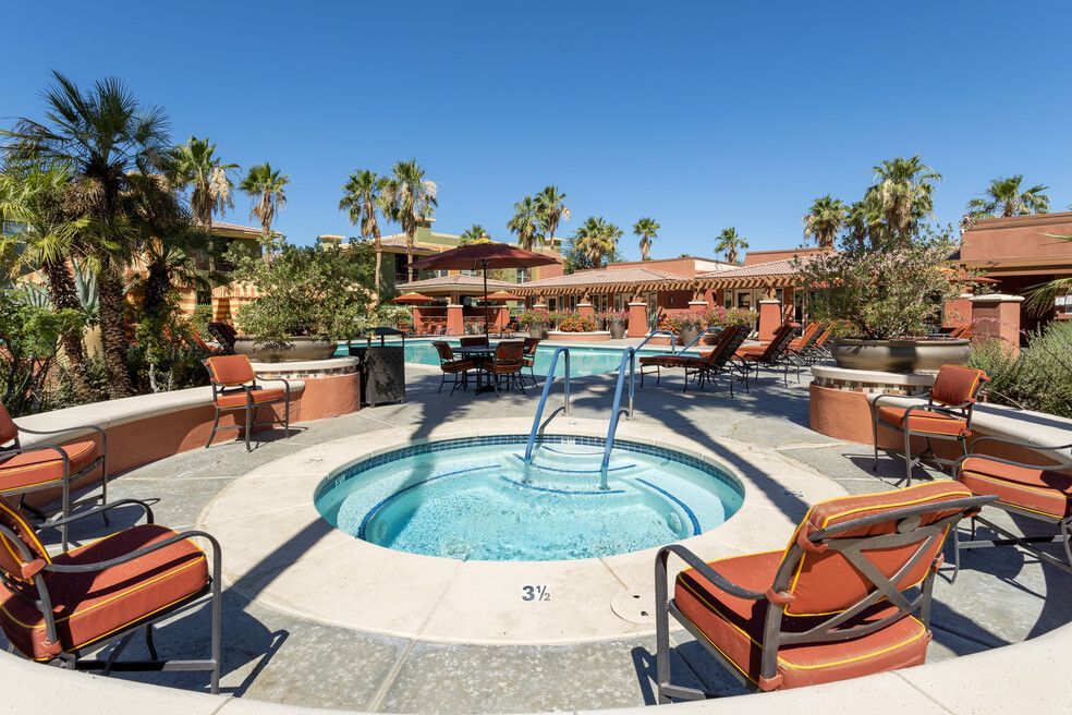 A hot tub is surrounded by chairs and a swimming pool.