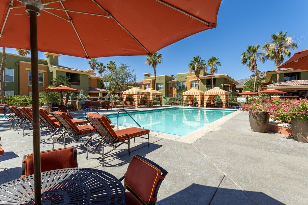 A swimming pool with a table and chairs under an umbrella