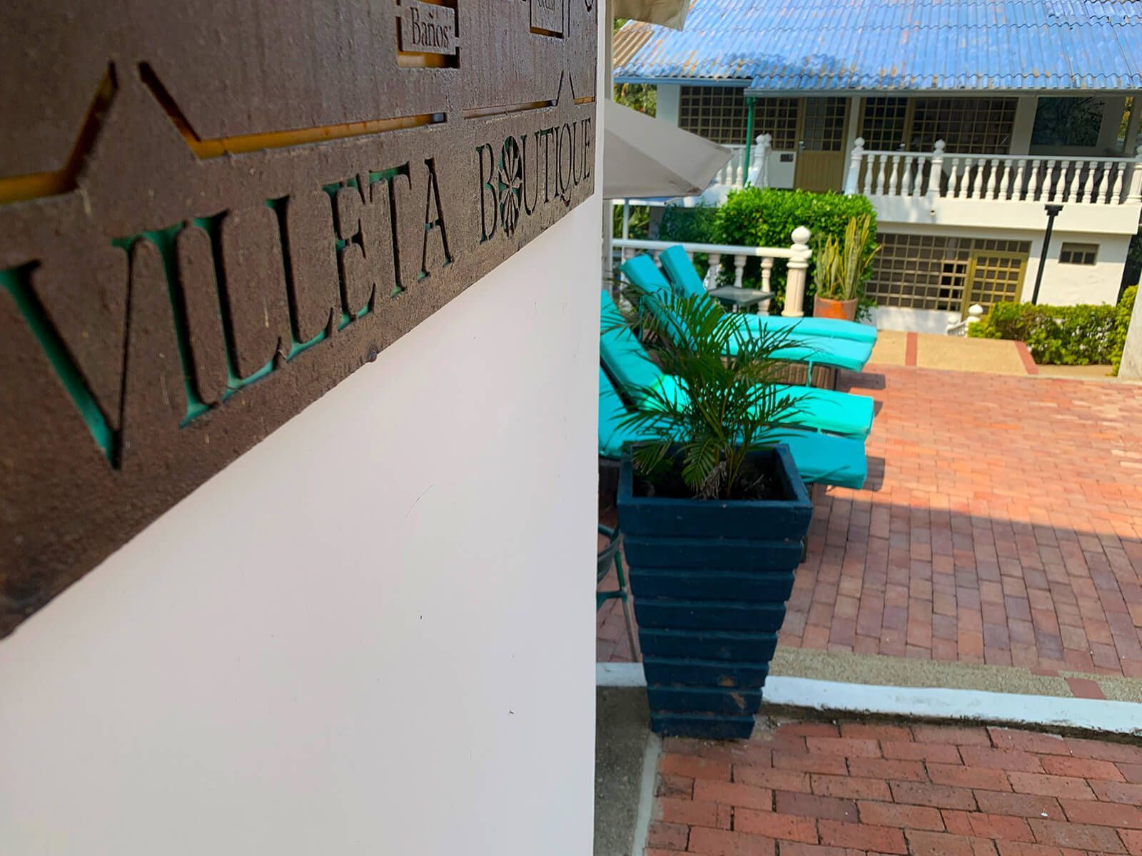 Courtyard entrance with Villa de Vista sign, potted plant, turquoise bench, and brick walkway