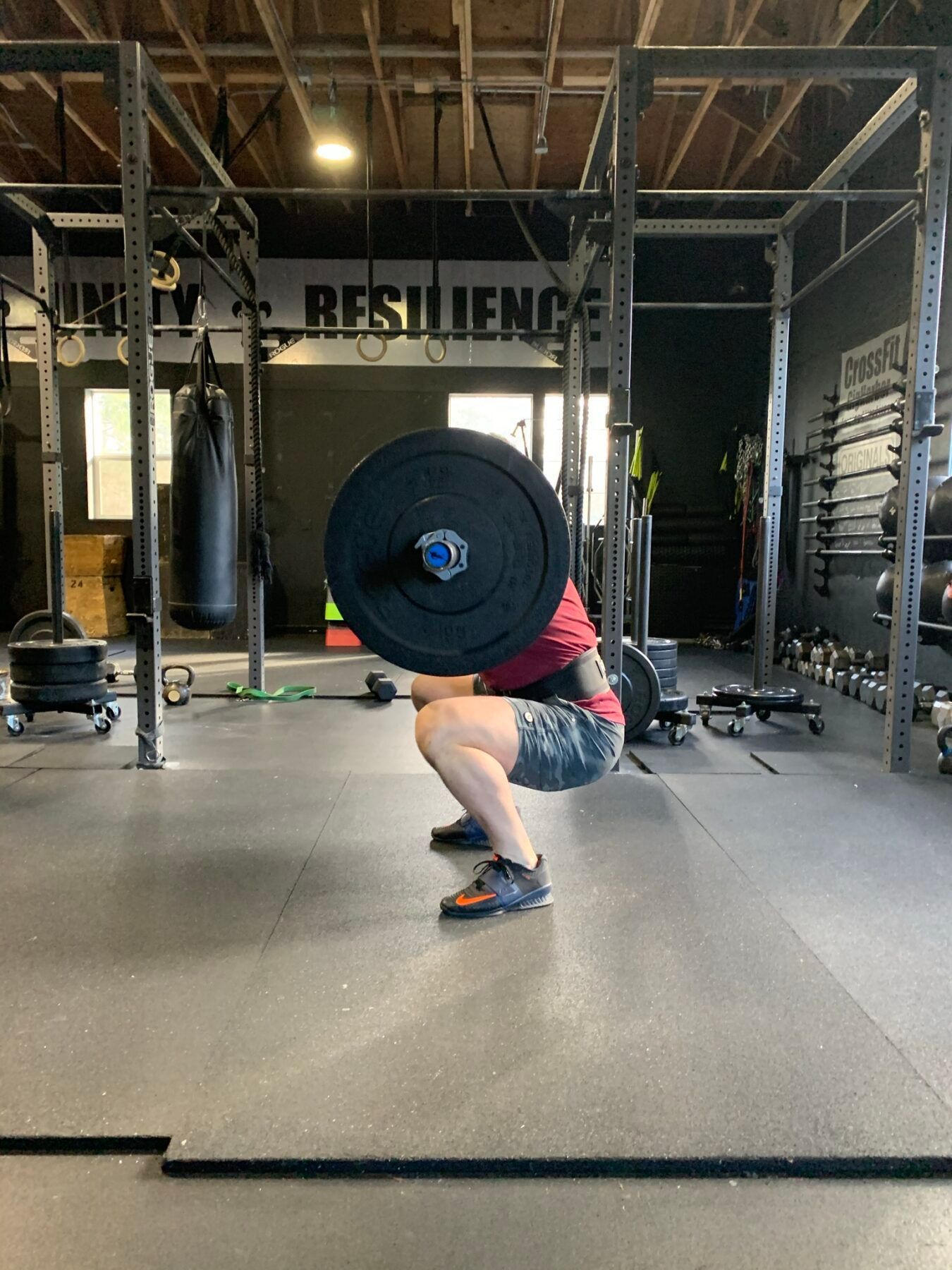A person squatting with a barbell in a gym.
