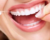 Teeth cleaning by our general dentist in Topeka KS Woman flossing after teeth cleaning visit with our general dentist near Topeka KS