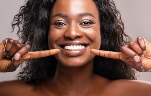 Best restorative dentist in Topeka KS Woman smiling pointing to mouth after visiting our restorative dentist in Topeka KS