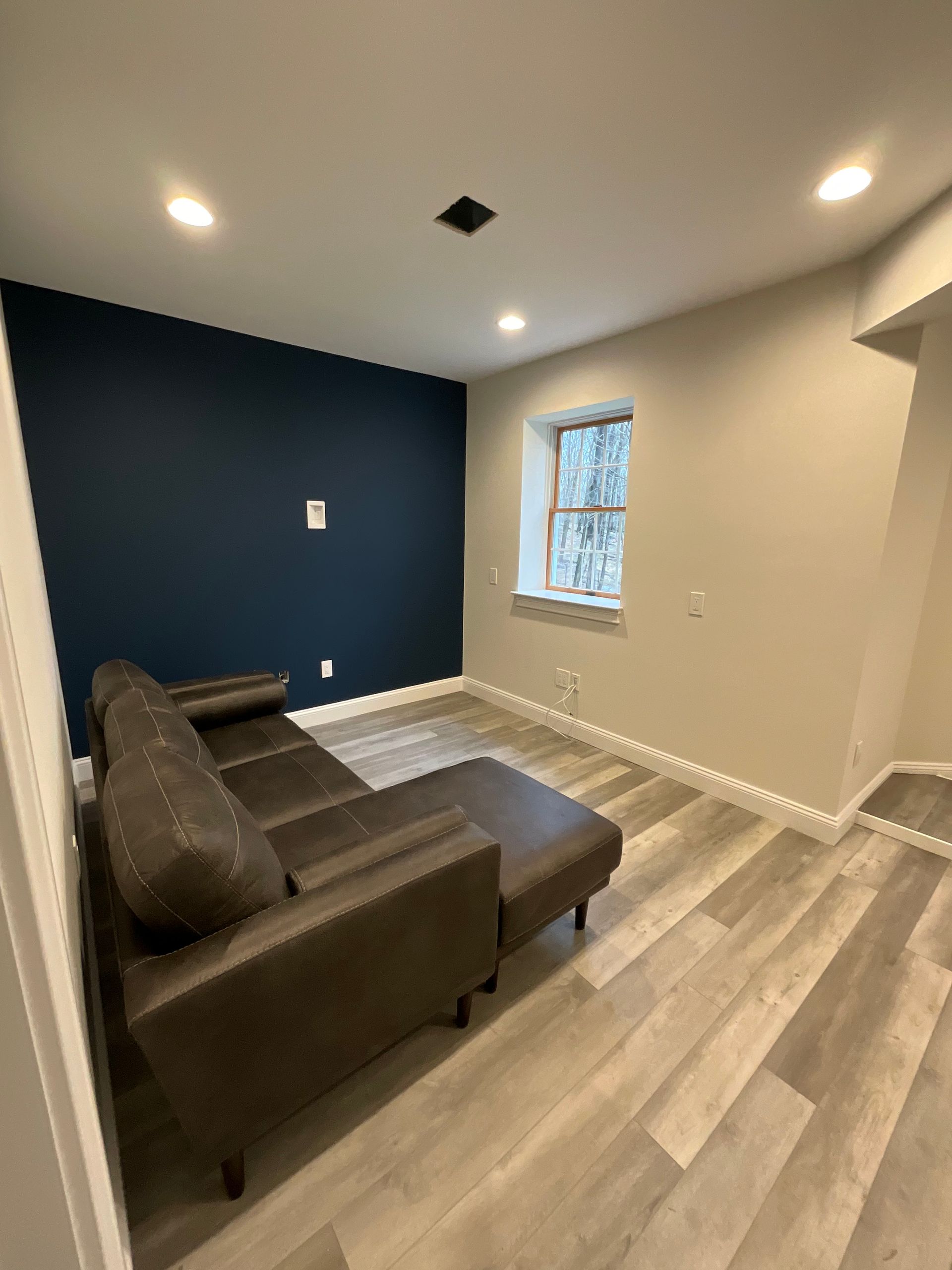 A living room with a couch , ottoman , and window.