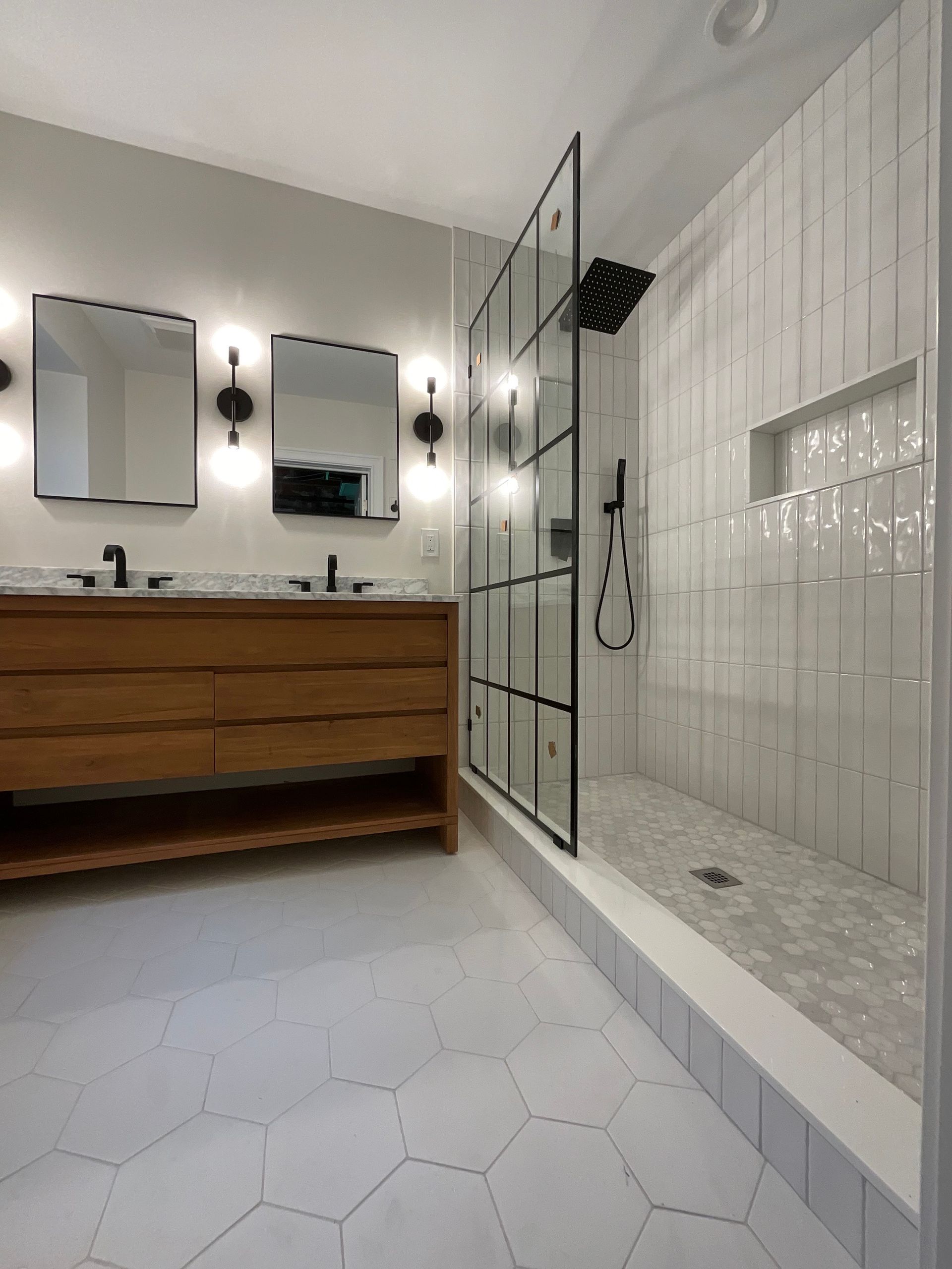 A bathroom with two sinks and a walk in shower.
