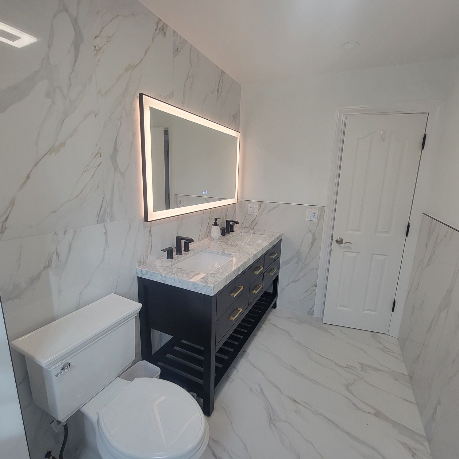 A bathroom with a toilet , sink and mirror.