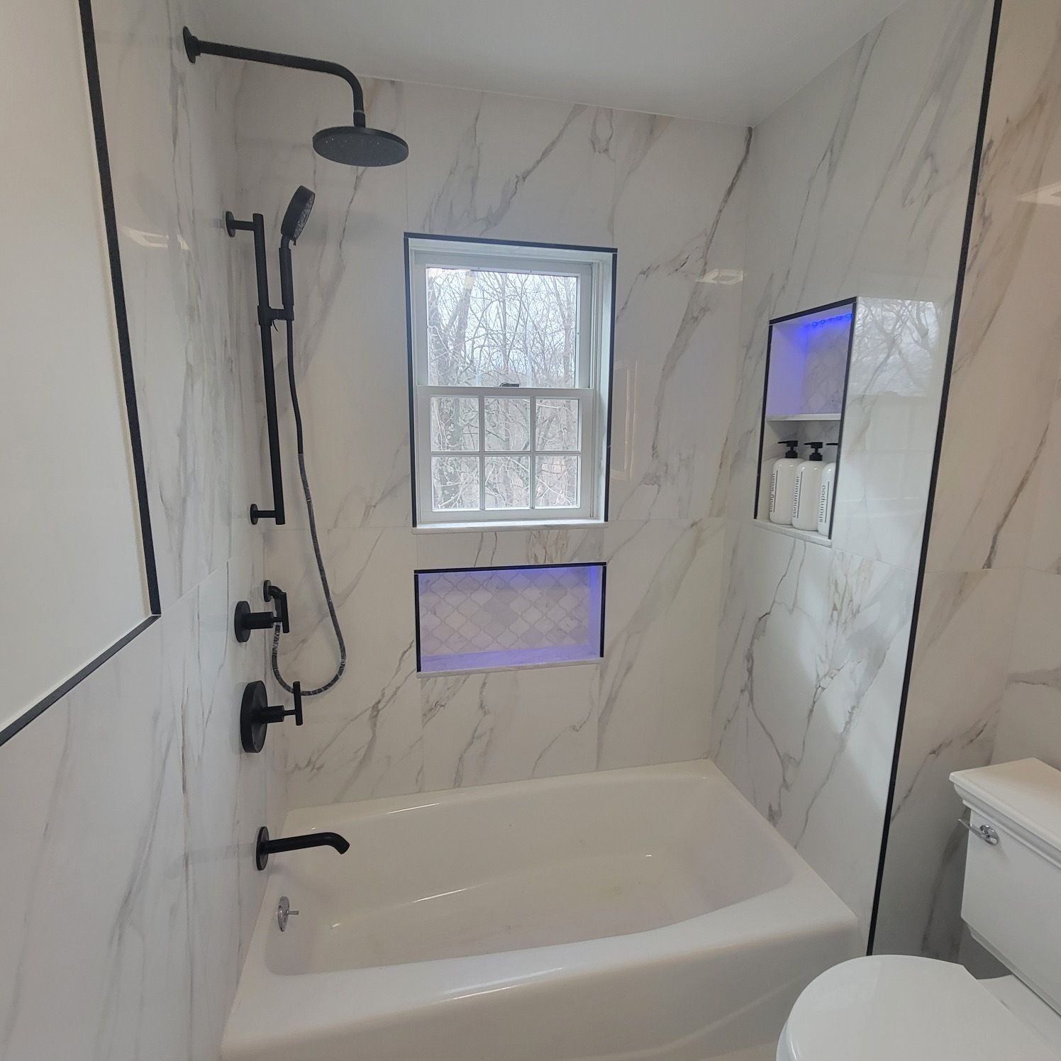 A bathroom with a tub a toilet and a window