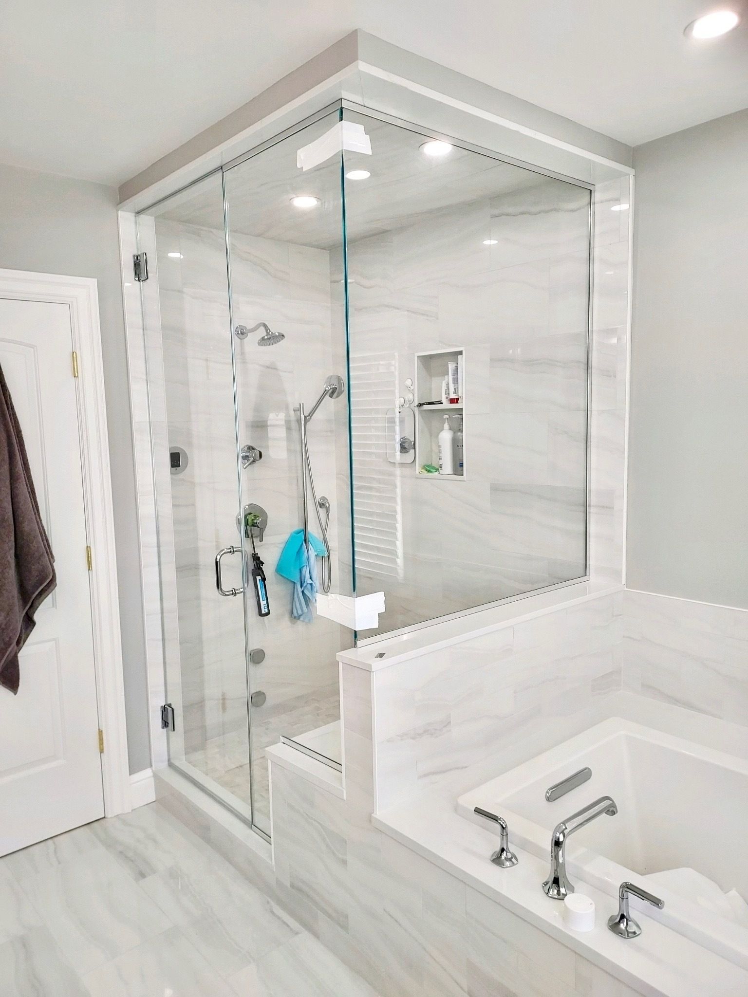 A bathroom with a tub , shower , and glass door.