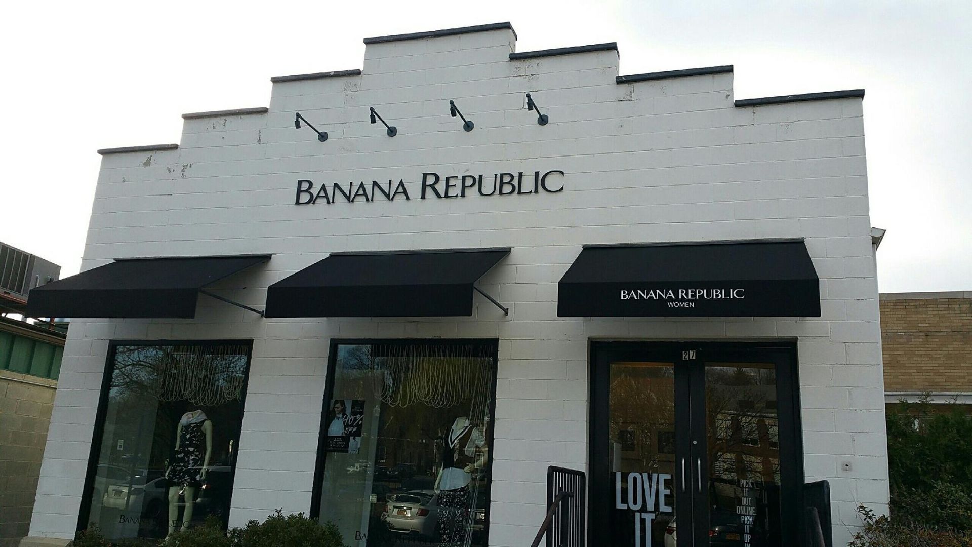 The front of a banana republic store with black awnings.