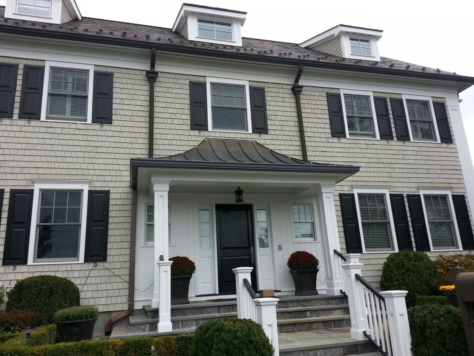 A large white brick house with black shutters on the windows