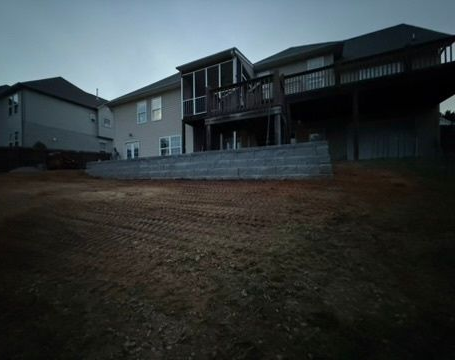 Suburban house with raised deck behind a retaining wall at dusk