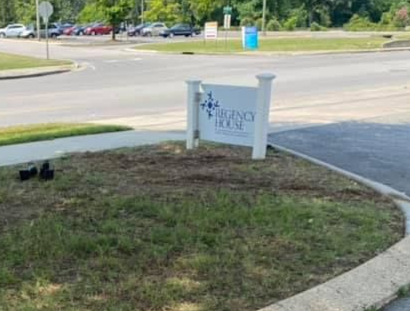 Entrance sign for Regency Oaks at a roadside corner with grass and pavement