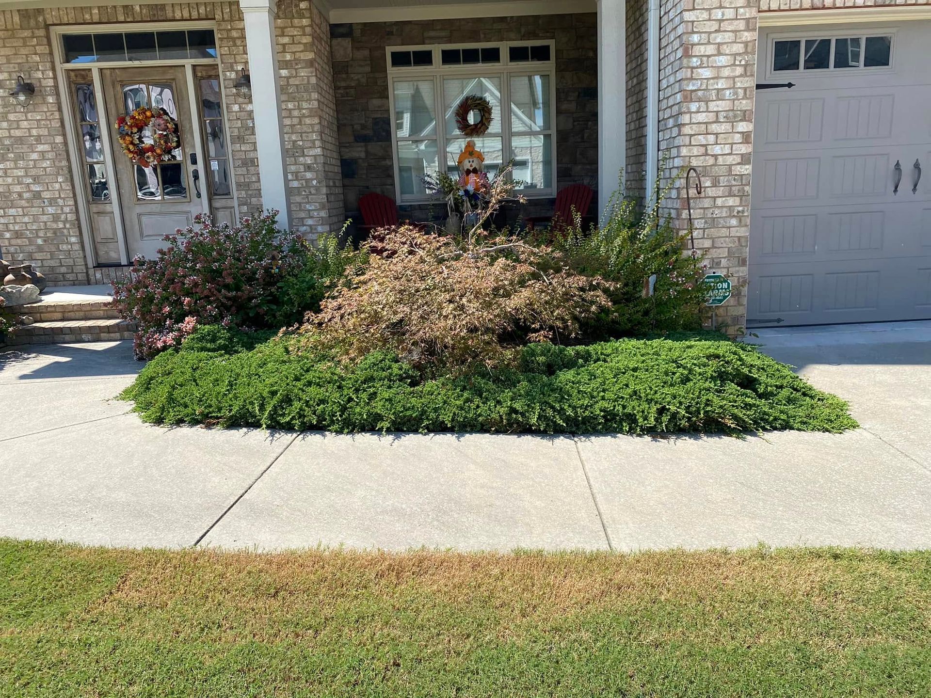 Front entry with stone facade, two decorated windows, garage, and landscaped flower bed