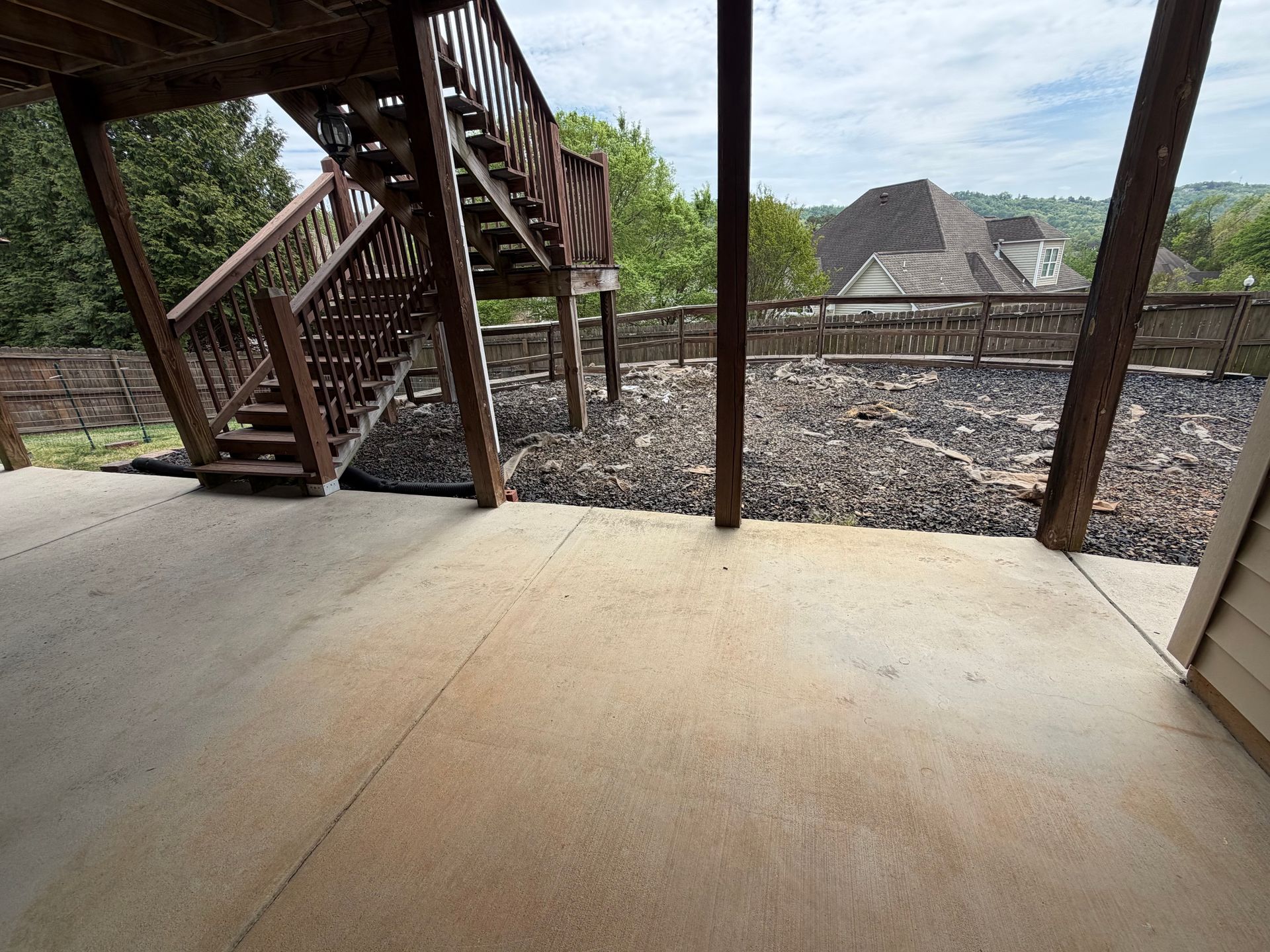 Backyard patio with pavers, grass, and a person standing by the house wall.