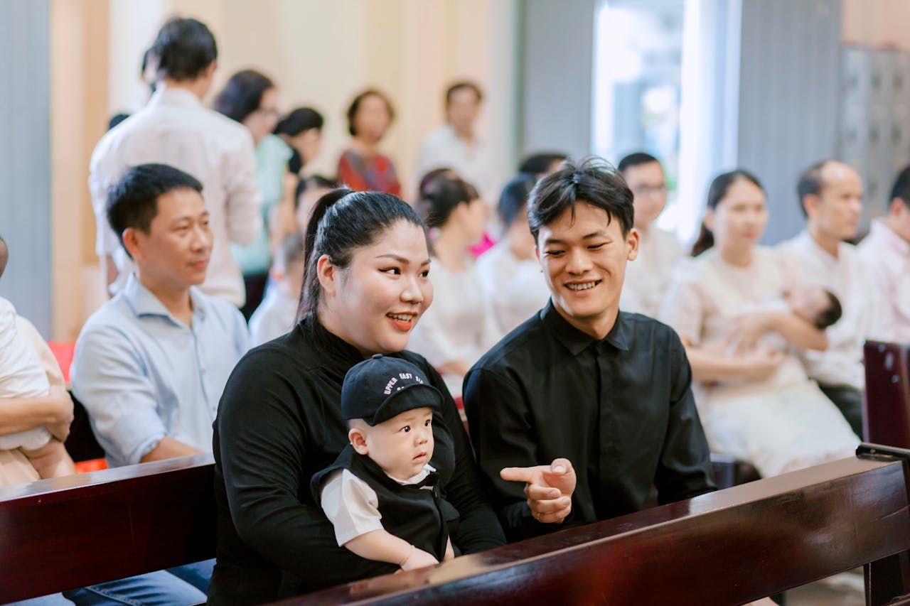 Family in church, with baby in arms, smiling at the camera.
