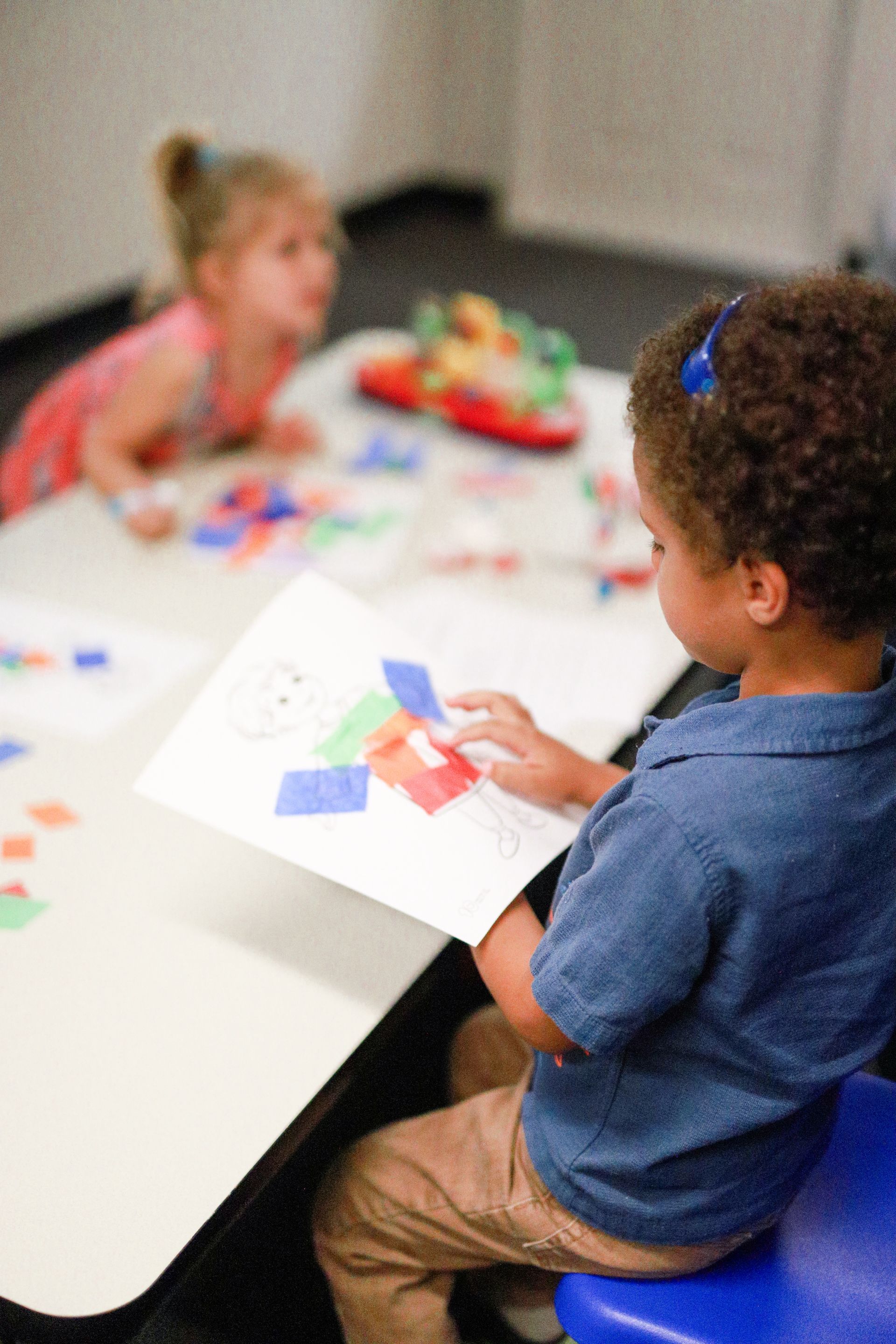 A little girl is sitting at a table playing with toys