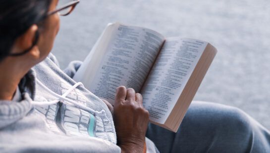 A woman is sitting on the floor reading a book.