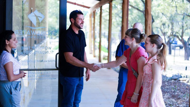 A group of people are shaking hands outside of a building.