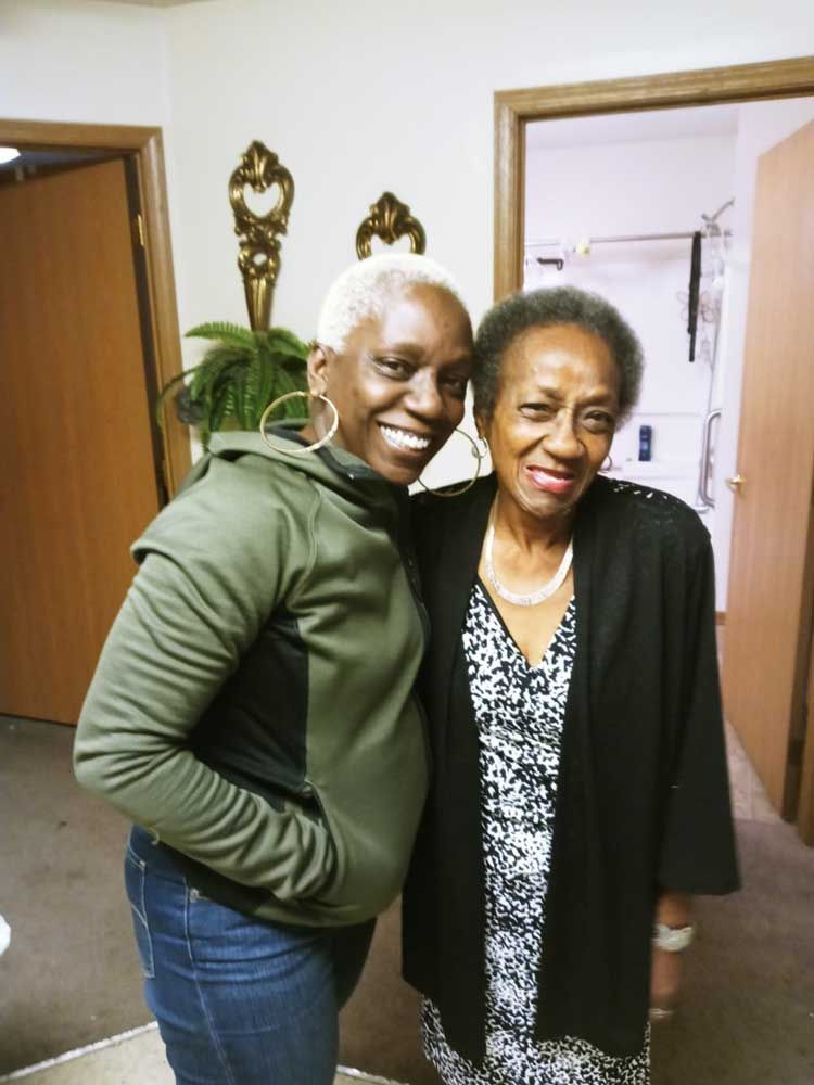 Two women are posing for a picture and smiling for the camera