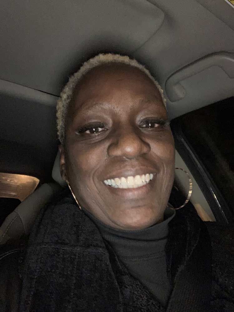 A woman is smiling while sitting in a car.