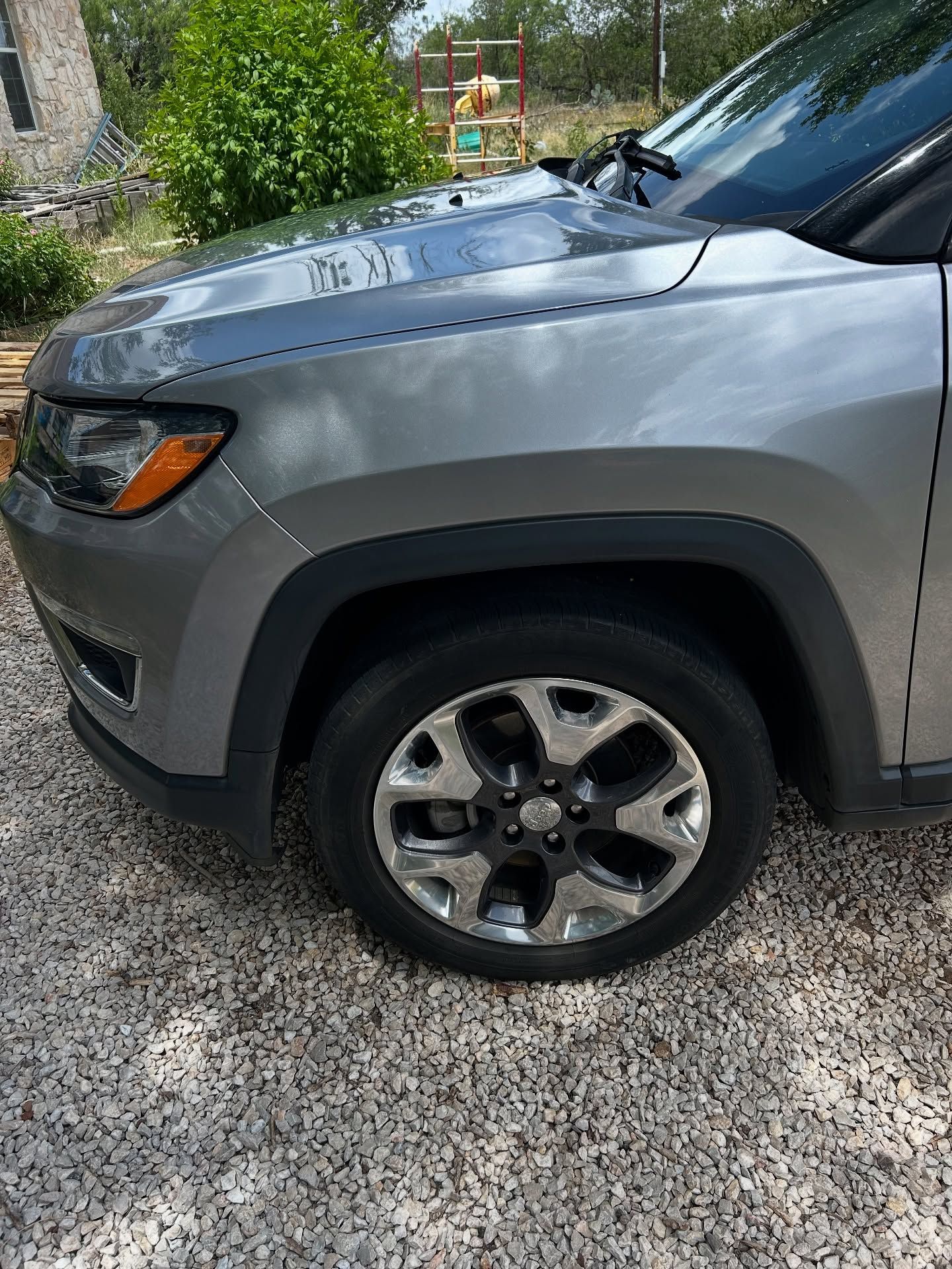 Silver SUV parked on a gravel driveway with trees and a backyard in the background