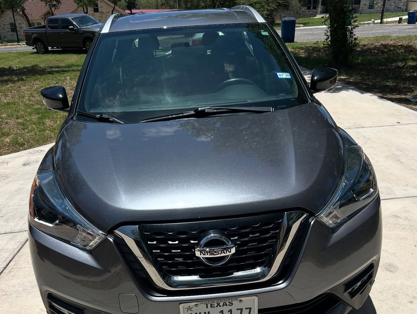 Front view of a gray Nissan SUV parked on a driveway in daylight