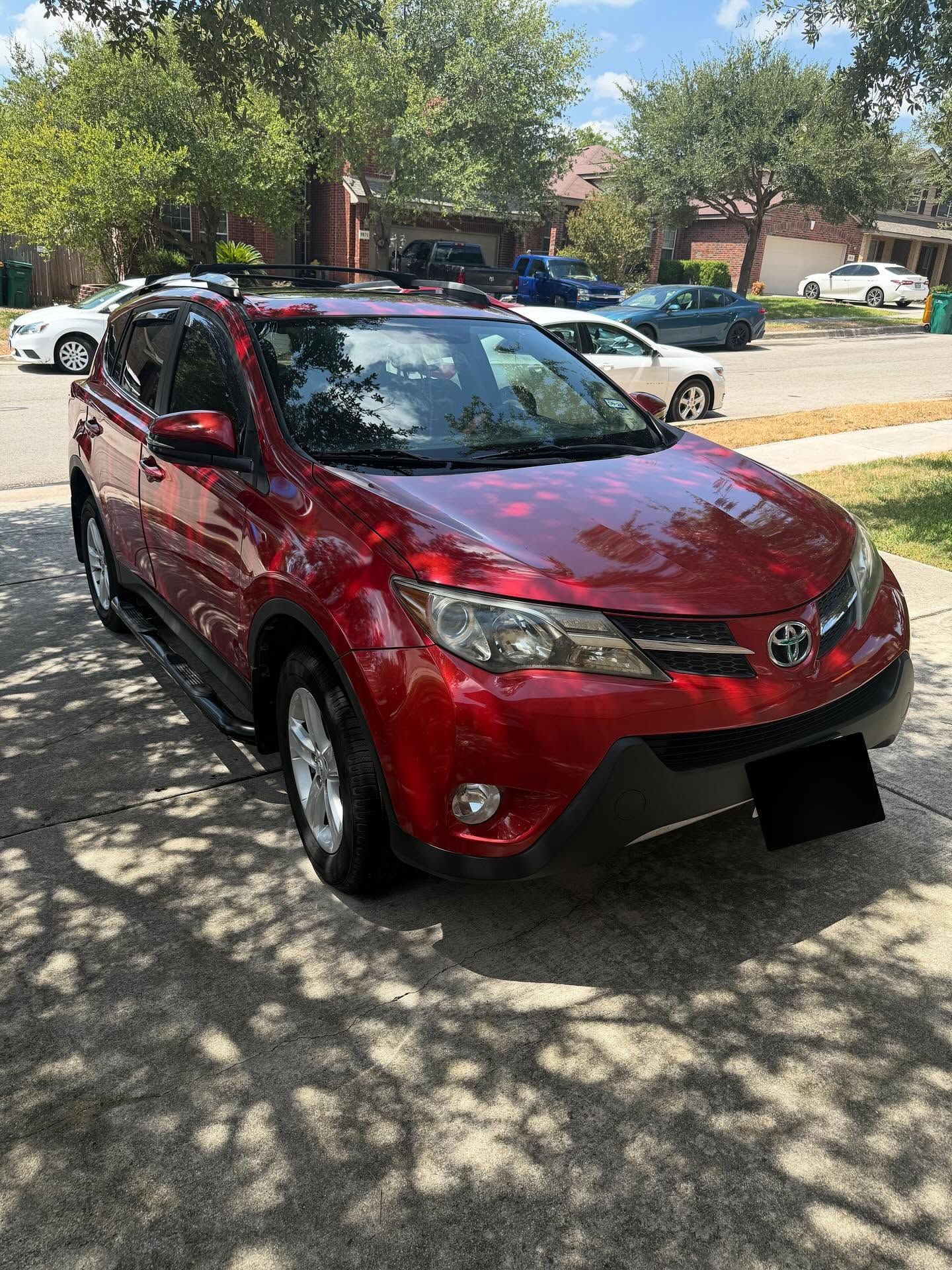 Red Toyota SUV parked on a sunny residential street under trees