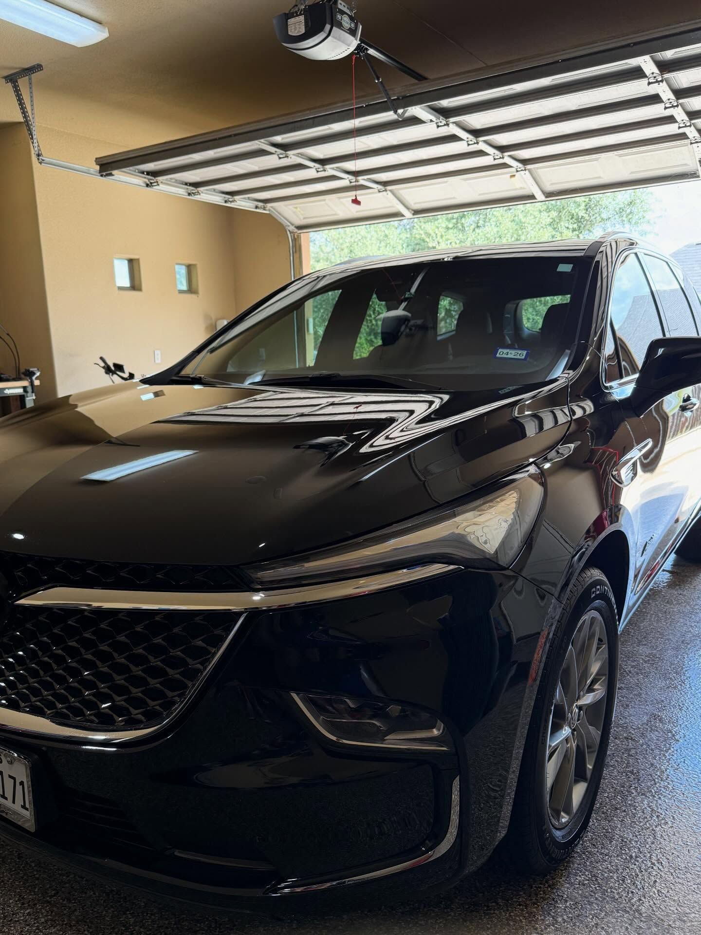 Black SUV parked in a garage with the rear hatch open and a lift gate raised above it