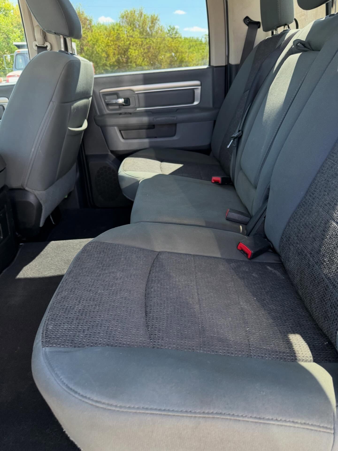 Rear seat of a vehicle with dark fabric upholstery and sunlight streaming in from the side window