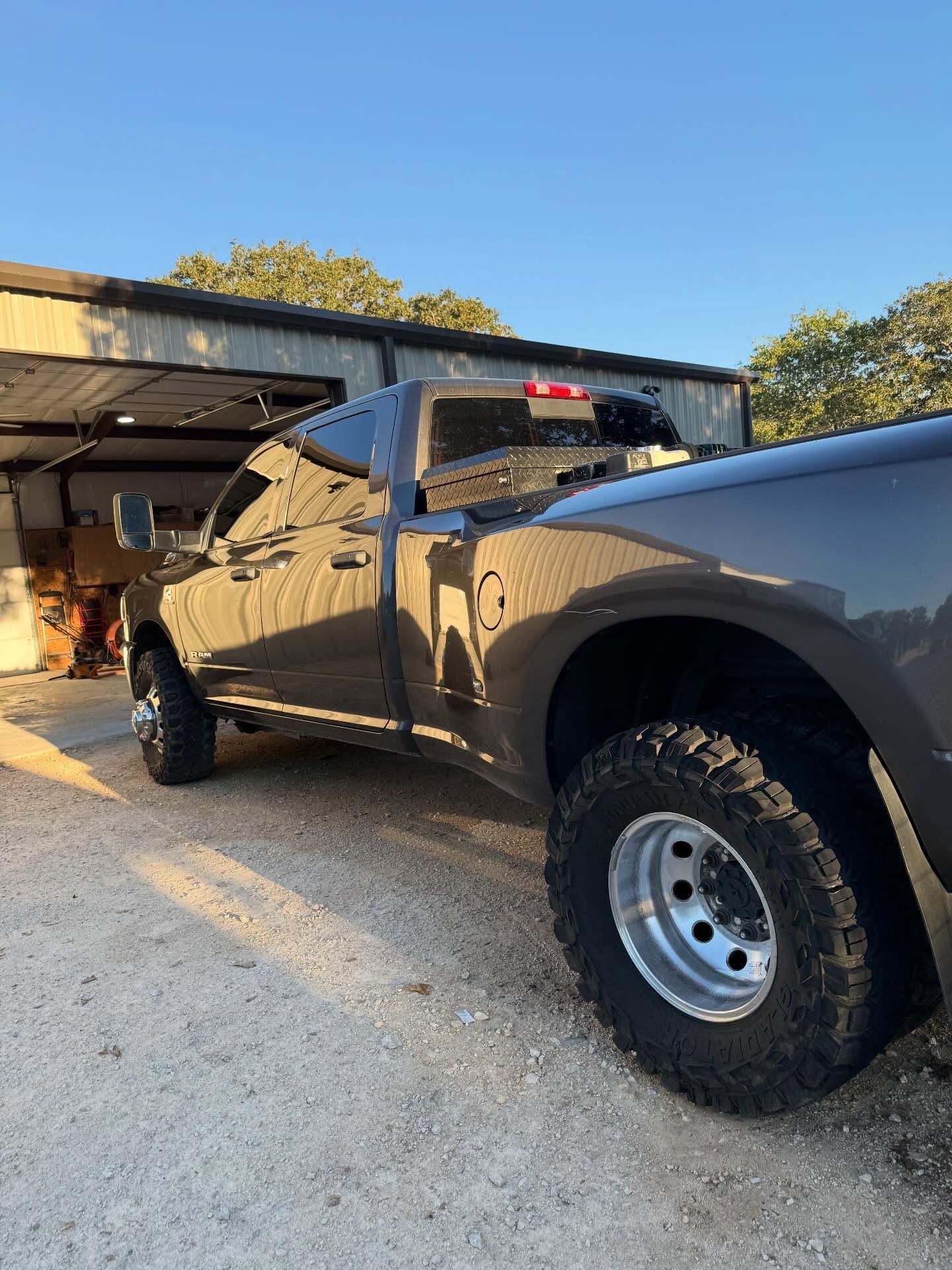 Black pickup truck parked beside a garage in a driveway at sunset