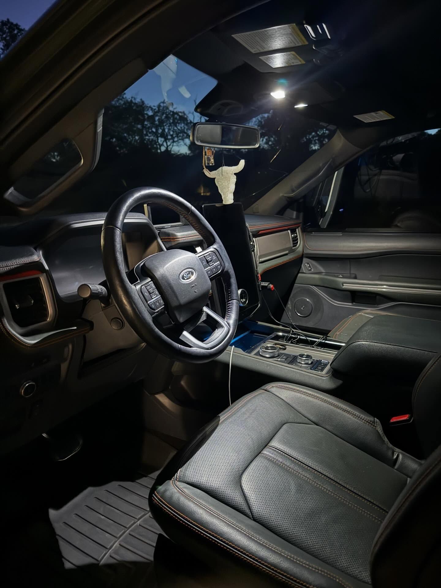 Luxury car interior with black leather seats and dashboard lights at night