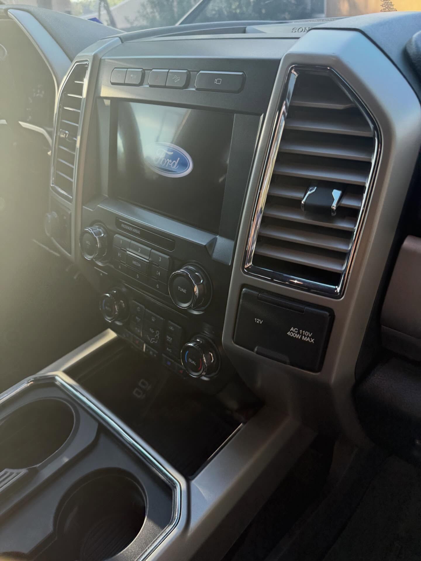 Truck dashboard with center touchscreen, climate controls, and cup holders in a gray interior