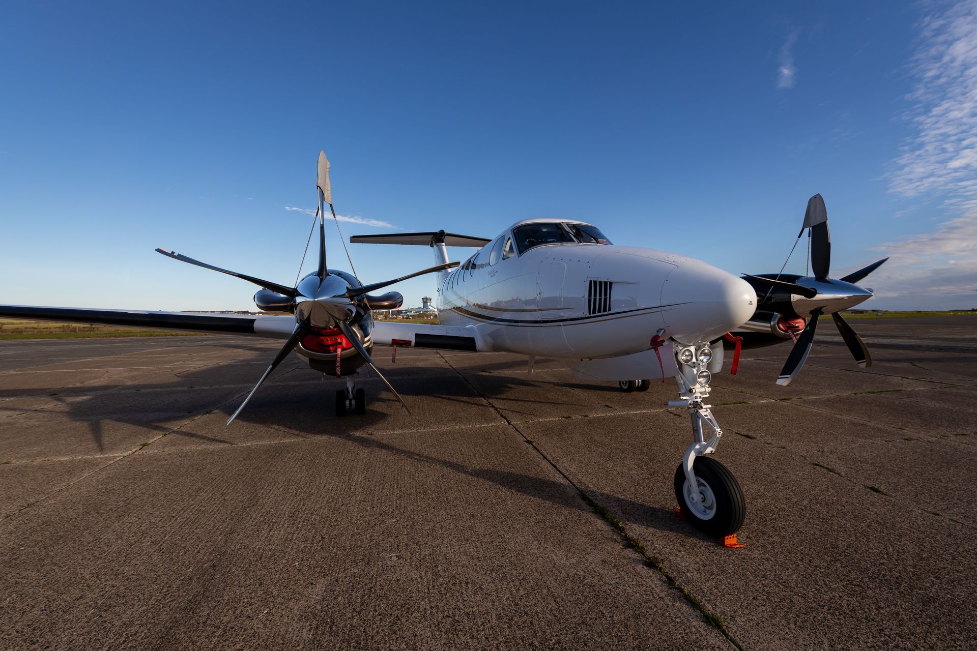 Small twin-engine propeller plane on a runway under a clear blue sky
