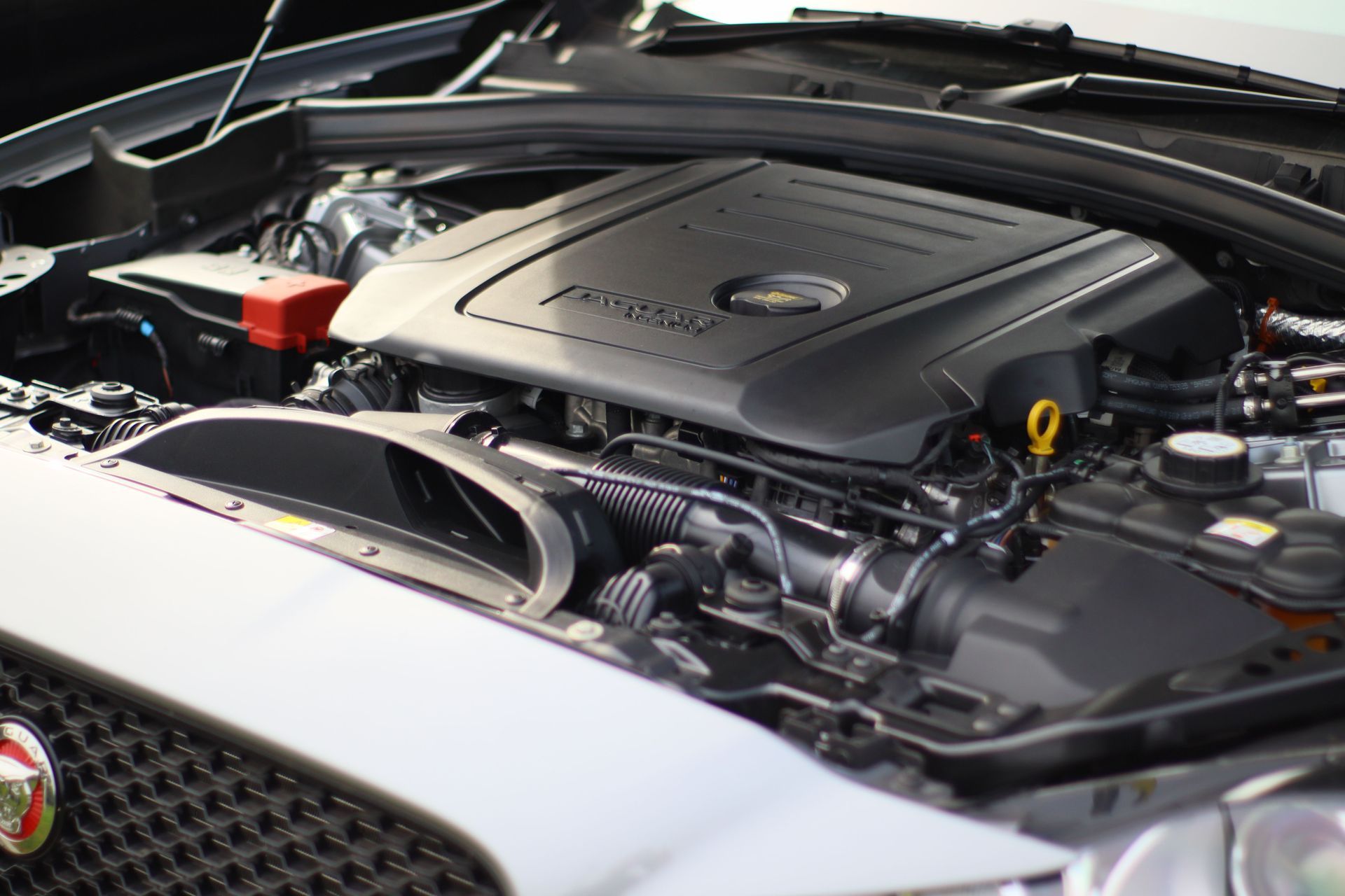 Car engine bay with a black engine cover and visible components under the hood