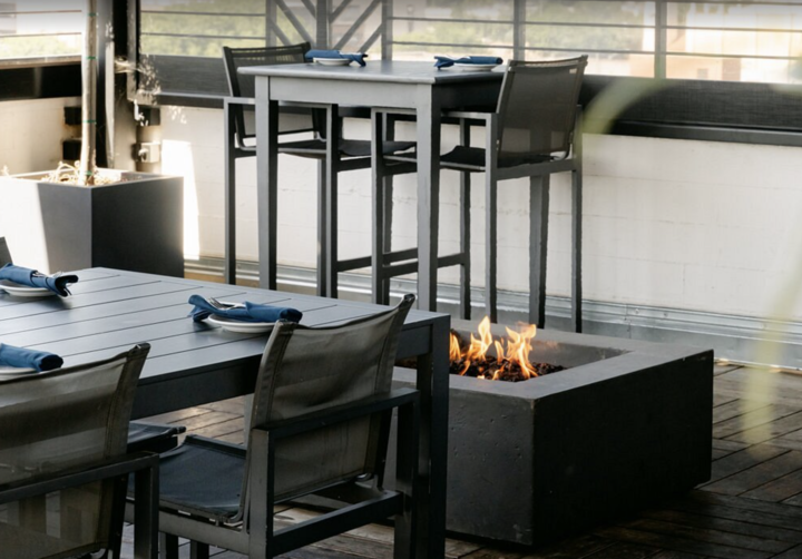 Outdoor patio with black tables and chairs around a square fire pit
