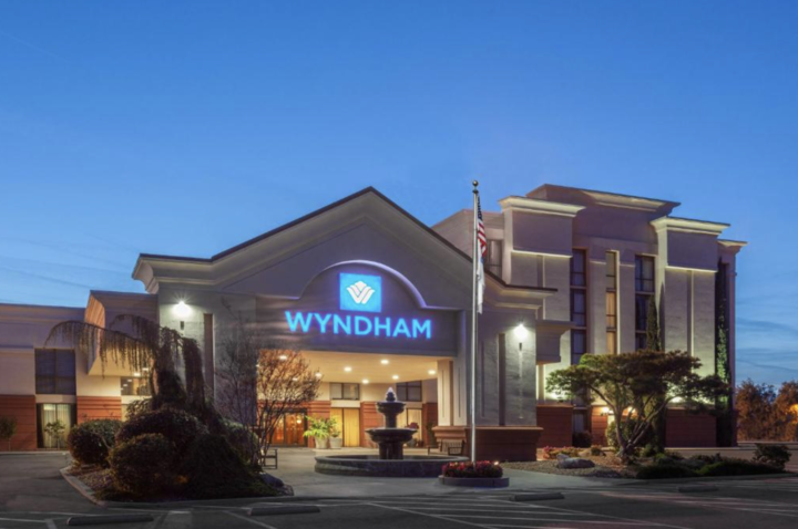 Wyndham hotel entrance at dusk with illuminated blue sign and landscaped front drive