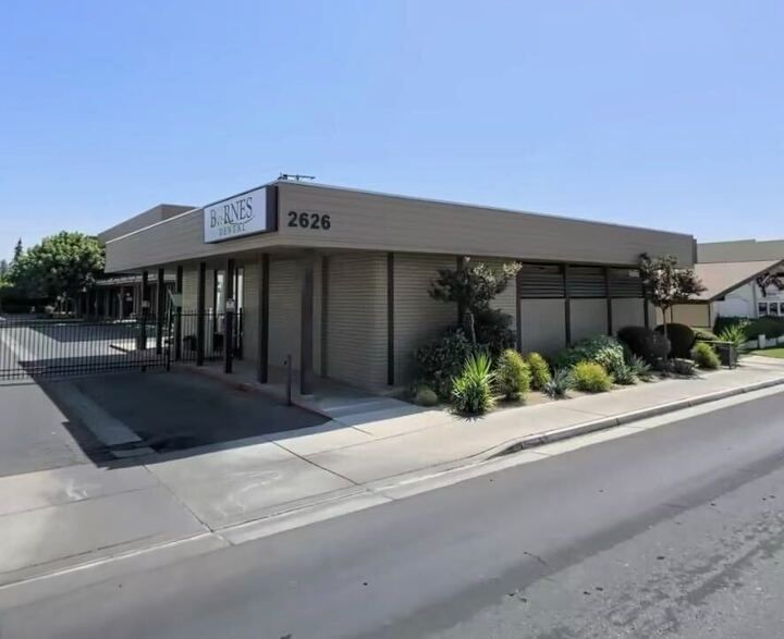 Exterior of a tan commercial building with address 2626 and a parking lot in front