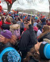 Crowd of bundled-up people at an outdoor winter event, many wearing hats and jackets
