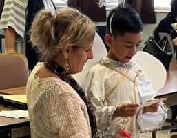 Woman and boy in formal attire reading papers at an indoor event