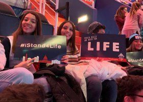 People holding signs reading “#IStand4Life” and “LIFE” in a crowded indoor event.